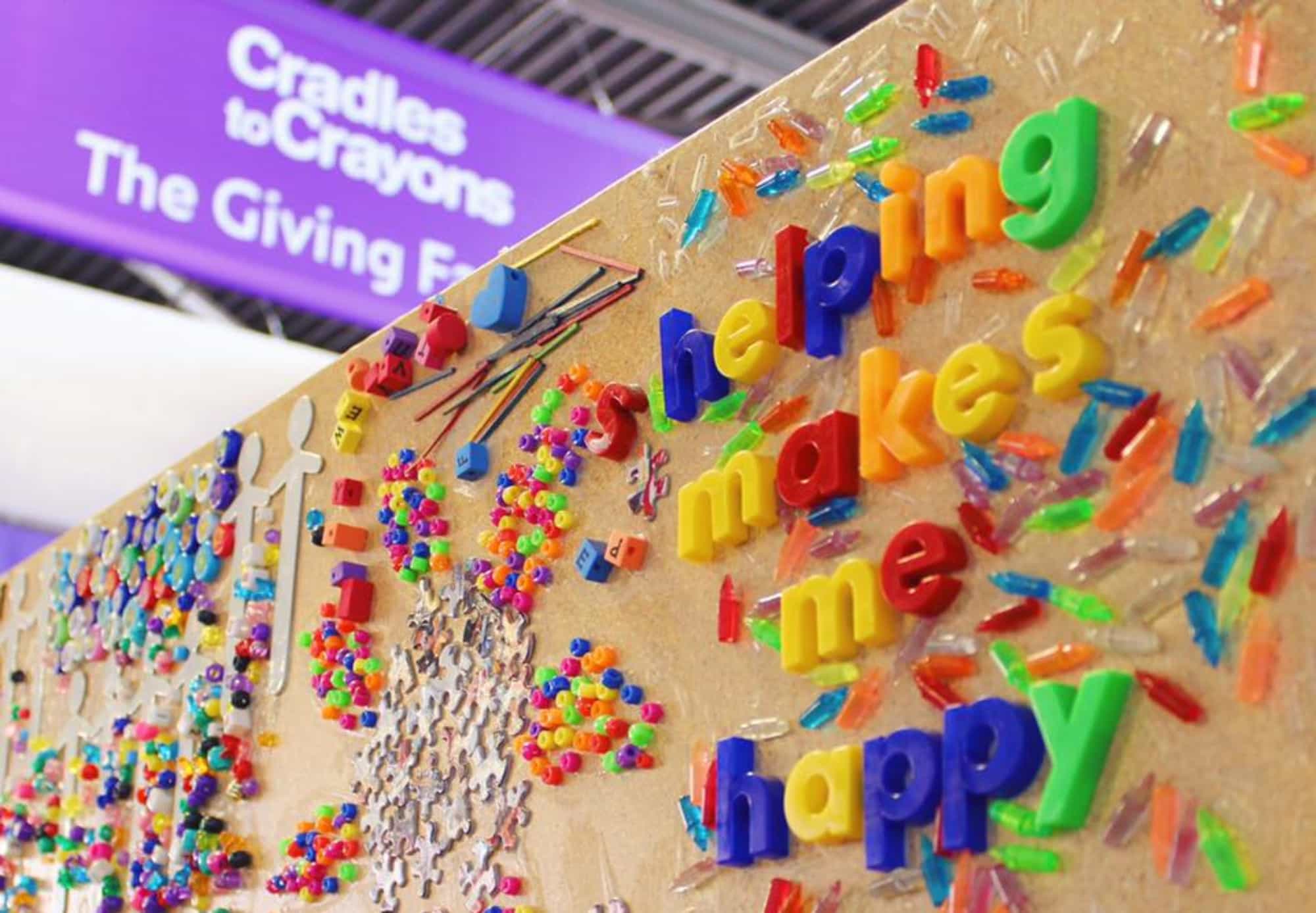 A board at the giving factory that reads in magnet letters, "helping makes me happy".